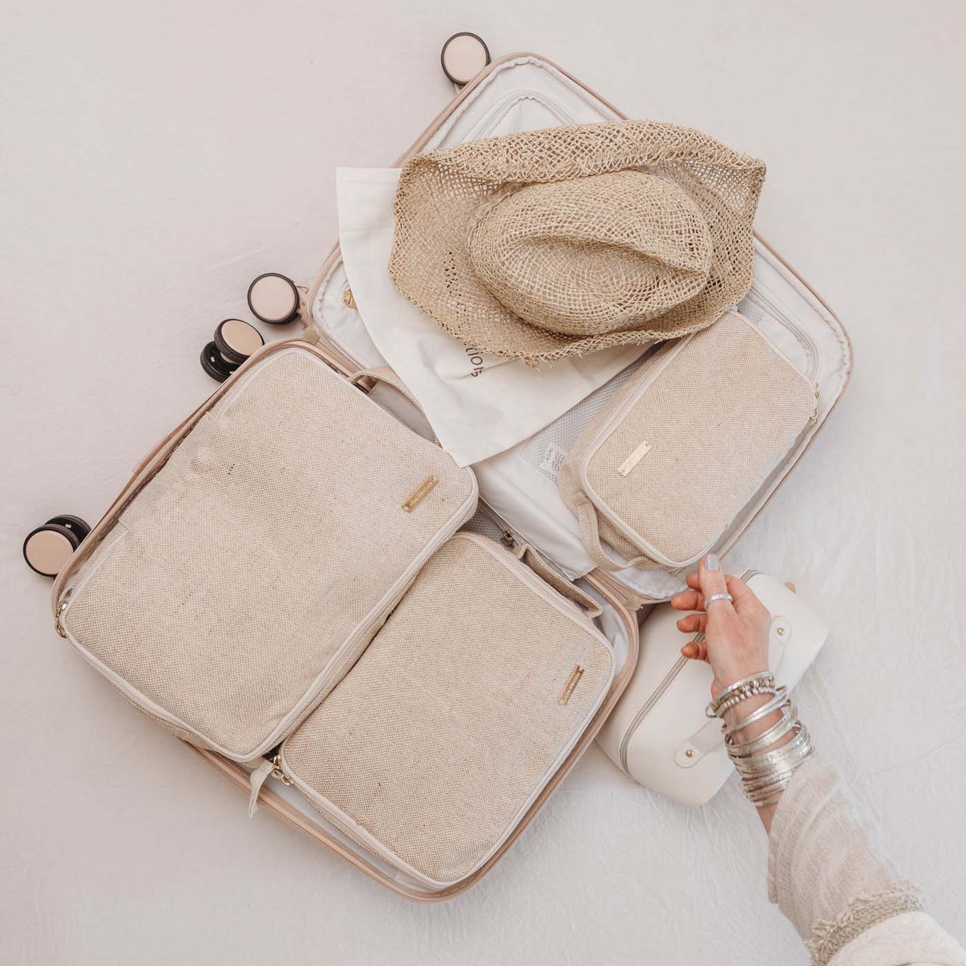 Set of 6 travel packing cubes in beige jute and cotton, including cubes, wet bag, tech bag, and shoe/laundry bag.