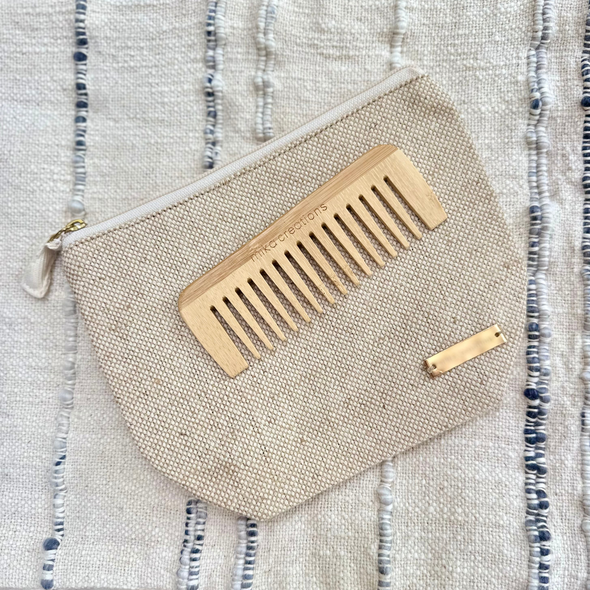 Small wet bag with a wooden comb on a textured fabric background